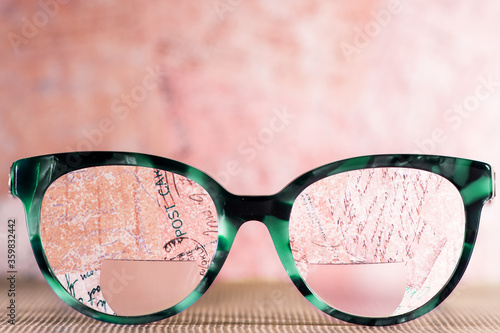 Eyeglasses Glasses with Bifocals and Black blue Frame smudged agaist written letters.  Blurry Vision Concept
