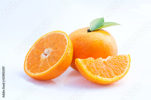 Orange fruit with sliced and green leaves on white background.