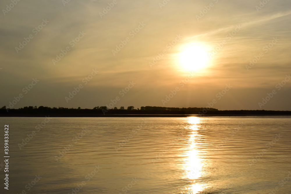 Obraz premium Golden sunset over a calm river.