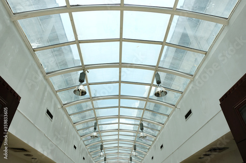 A mall utilizing a skylight roof or glass ceiling to allow sunlight to shine through as natural indoor lighting in order to conserve electricity and reduce energy consumption.