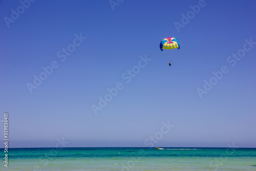 Parachute in the sky above the beach and the sea