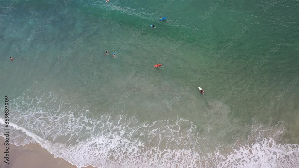 imagem aérea de bela praia com pessoas praticando surf, bodyboard, stand up e se banhando 