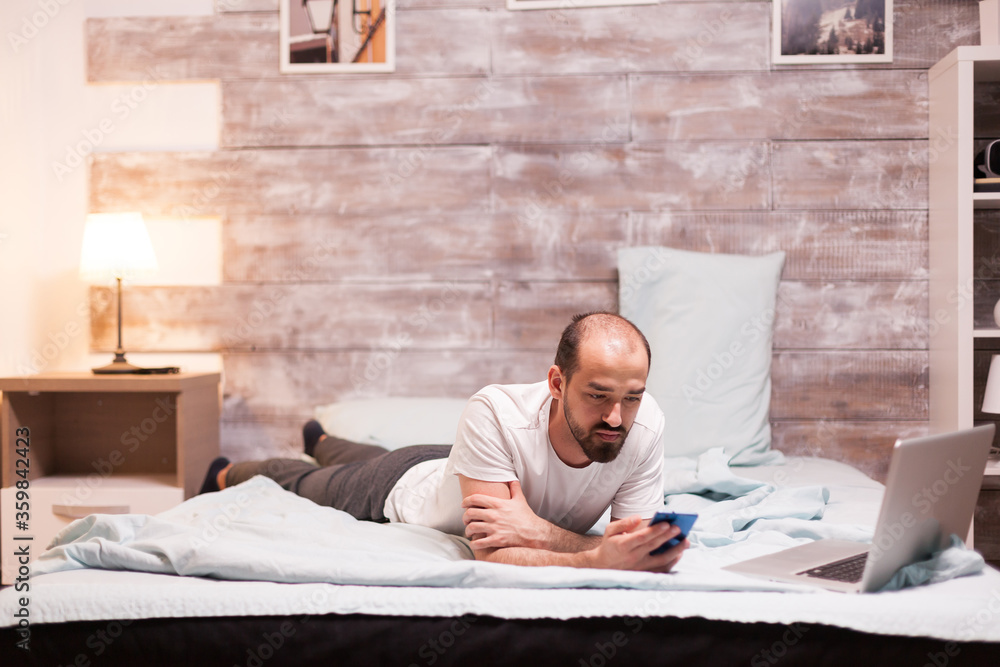 Fototapeta premium Using smartphone while laying on bed at night