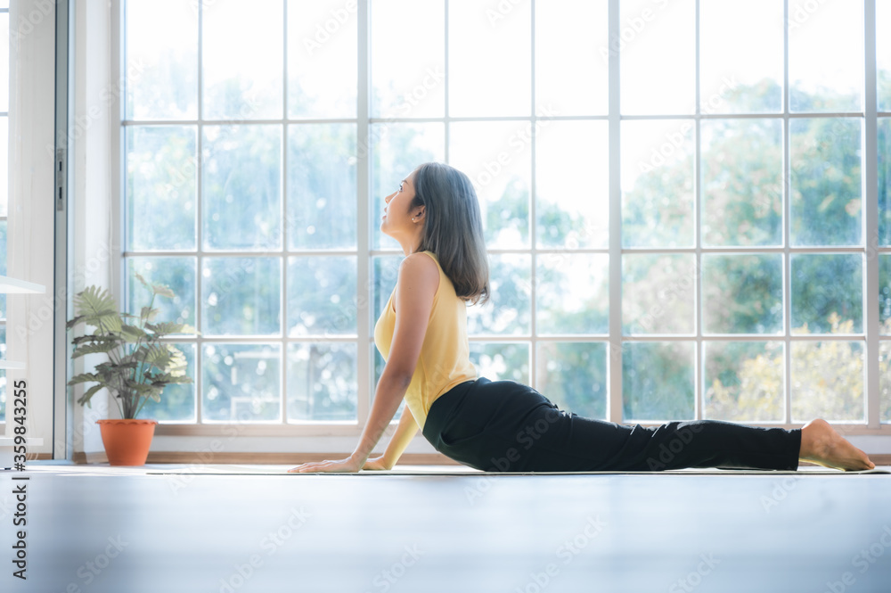 The Asian young yoga performer the meditating in lotus and cobra position at the cozy home in living room under the stay home situation The Asian young yoga performer the meditating in lotus and cobra position at the cozy home in living room under the stay home situation