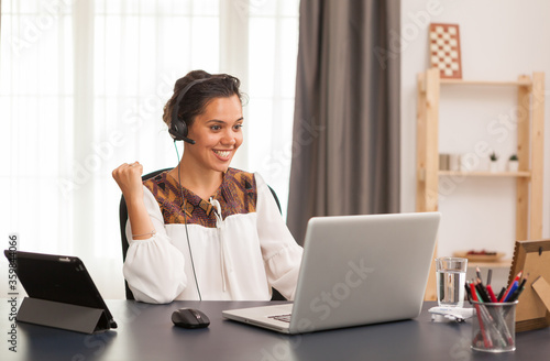 Excited female entrepreneur during a video call on laptop from home office.