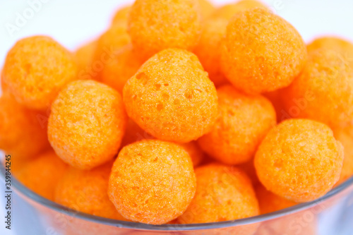 tasty cheese balls in transparent bowl on white background