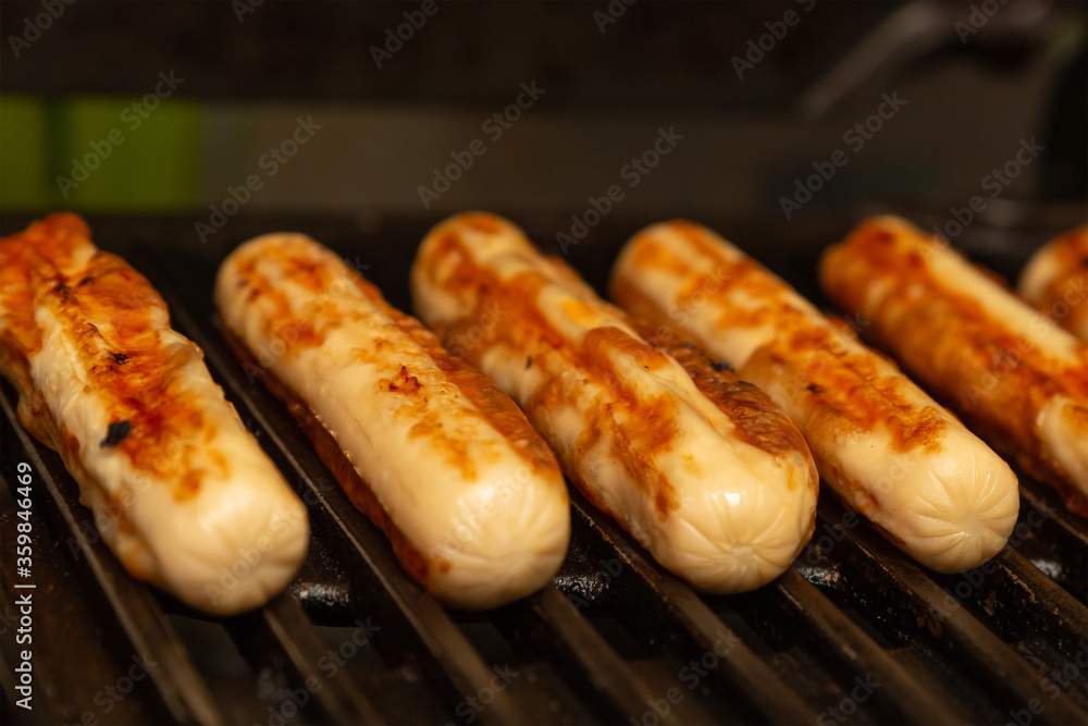 Pork sausage with chicken lie parallel on a grill background close-up