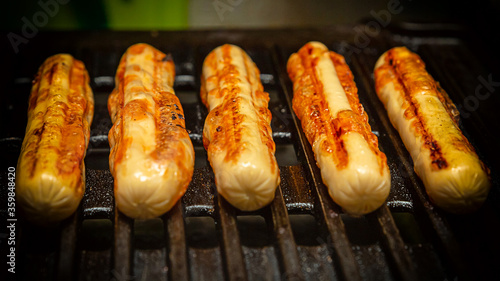delicious grilled sausages lie in parallel on an iron pan