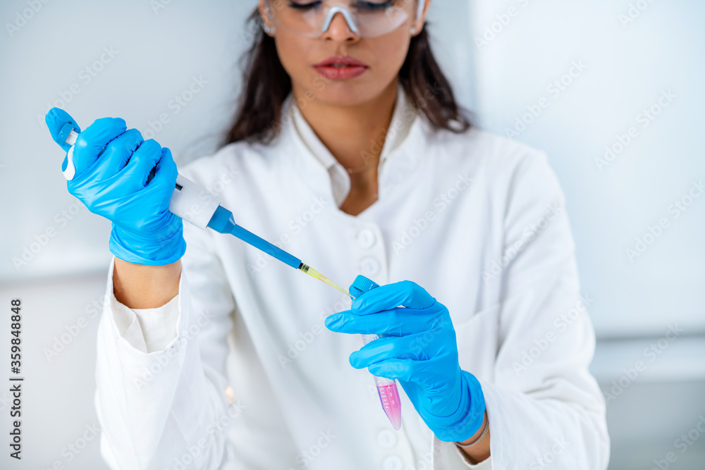 Student in White Coat, Working in Research Laboratory Using Micro Pipette and Test Tube Student in White Coat, Working in Research Laboratory Using Micro Pipette and Test Tube