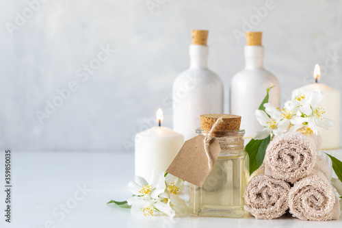Jasmine essential oil  candles and towels  flowers on a white background. Spa and wellness concept. Copy space.