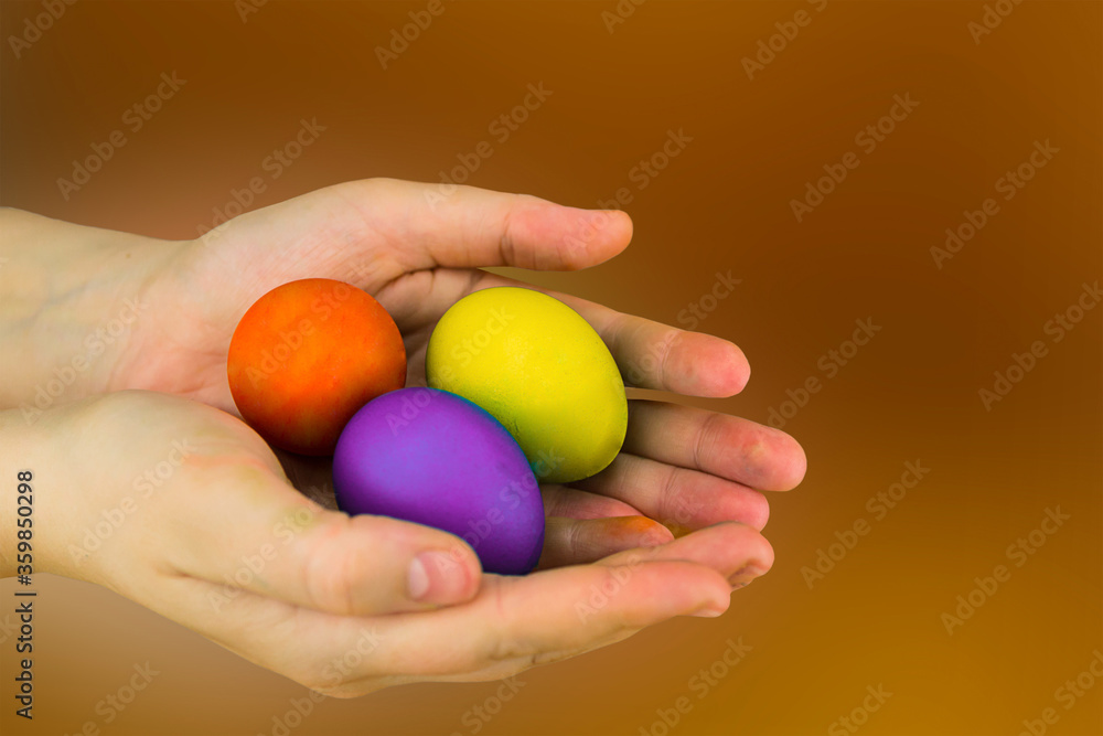 Easter holiday set of eggs painted yellow, lilac, red and brown lies in the hands Easter holiday set of eggs painted yellow, lilac, red and brown lies in the hands
