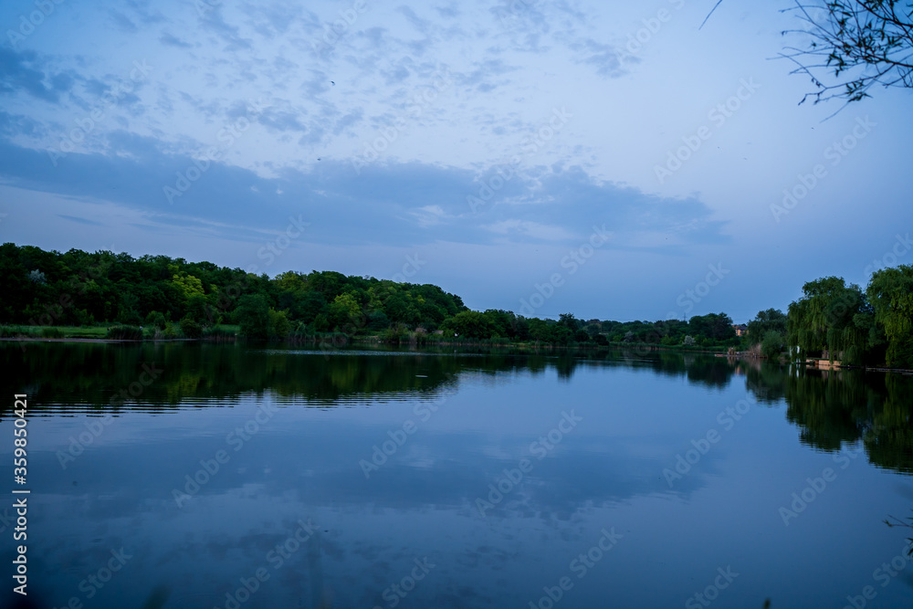 Obraz premium beautiful evening landscape. sunset on river. calm water in pond.