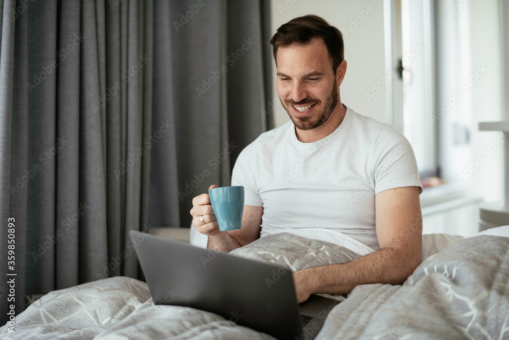 Young man watching movie in bed. Handsome man enjoying in morning. Young man watching movie in bed. Handsome man enjoying in morning.