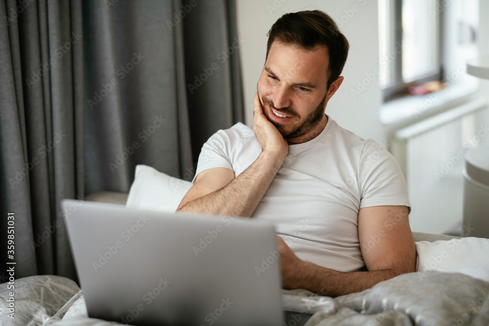 Young man watching movie in bed. Handsome man enjoying in morning. Young man watching movie in bed. Handsome man enjoying in morning.