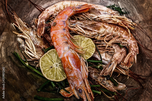 fresh, tasty large whole prawns with lemon slices seafood on iron background tinted