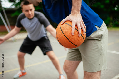Close up of hands holding ball. Friends playing basketball in the park. 