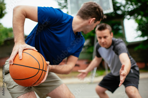 Two young men playing basketball in the park. Friends having a friendly match outdoors 