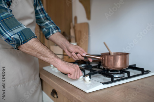 Close up picture of mans hands putting the pan on the oven