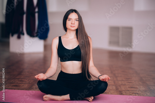 Beautiful young girl does hatha yoga on the mat, relaxes, taking care of health