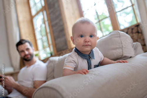 Cute baby crowling , his father watching him and smiling photo