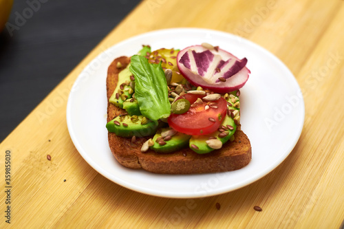Toasts with vegetables, avocados, tomatoes, a set of seeds. Healthy food, diet concept.