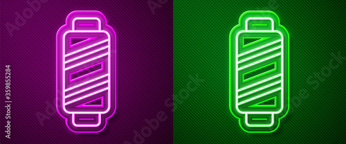 Glowing neon line Sewing thread on spool icon isolated on purple and green background. Yarn spool. Thread bobbin. Vector Illustration.