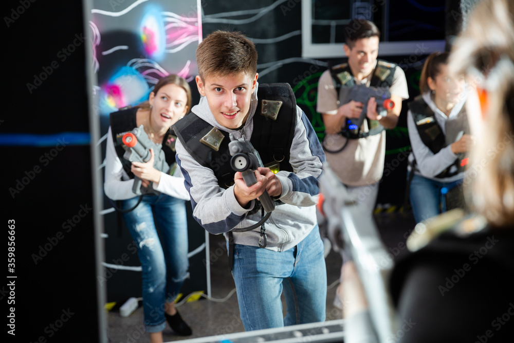 Teen boy playing laser tag with friends