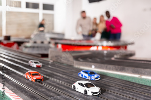 Men and women play with slot car racing track