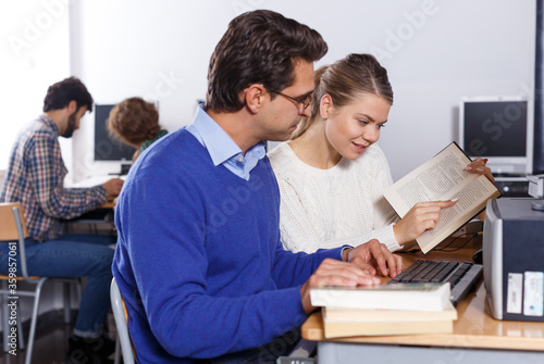 Female and male students working in computer room in library