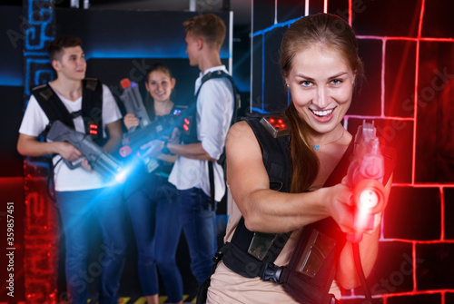 Smiling girl with laser pistol during enjoying laser tag game wi