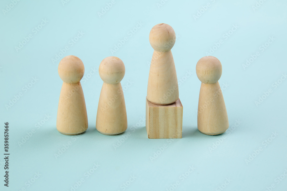 Wooden figure standing on the box for show influence and empowerment on blue background. Concept of business leadership for leader team. Wooden figure standing on the box for show influence and empowerment on blue background. Concept of business leadership for leader team.