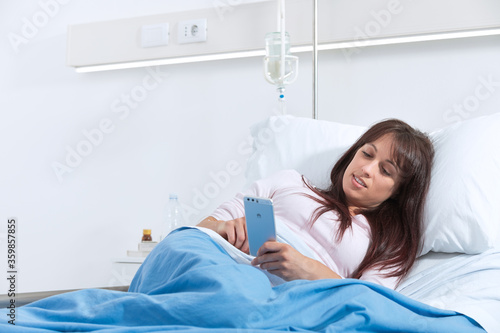 Female patient at the hospital and chatting with smartphone.