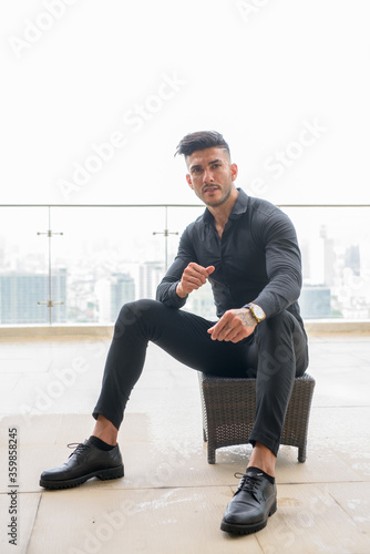 Young handsome bearded Persian businessman thinking in the city