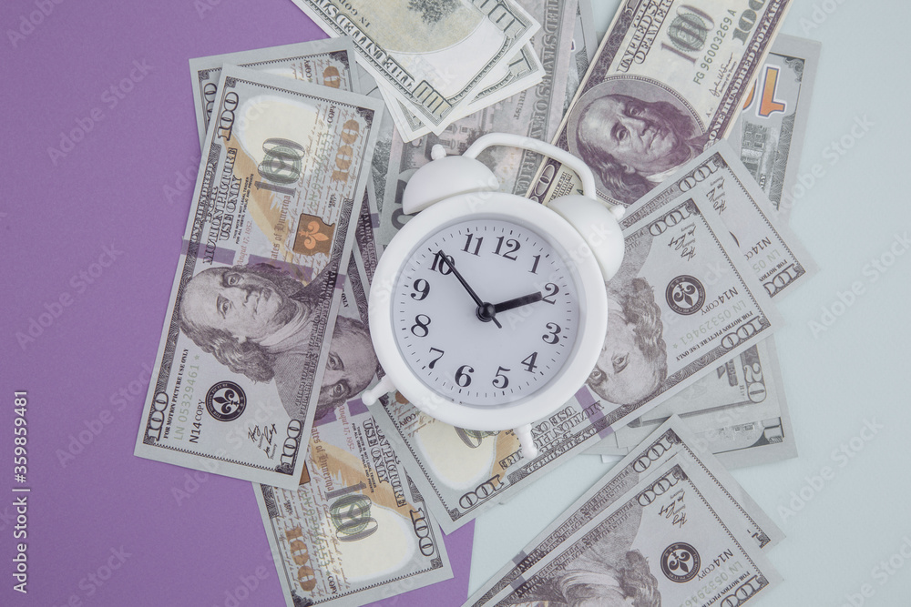 Alarm clock on dollars banknotes on colorful background. Time is money concept. Alarm clock on dollars banknotes on colorful background. Time is money concept.
