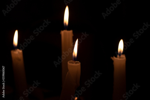 Burning candles on a dark background. The light of candles illuminates the darkness.