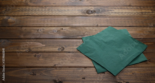Green paper serviettes, napkins on wooden plank table background and texture