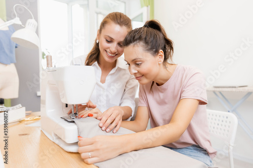 Student girl with teacher in dressmaking class, woman sewing lessons