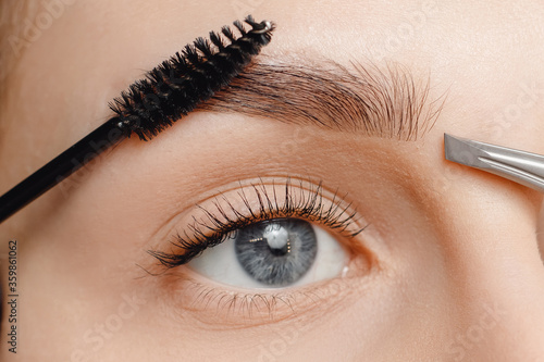 Master brushes eyebrows to woman in beauty salon. Correction of brow hair photo