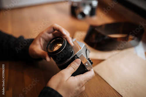 man hands adjusts the lens retro camera on a wooden table