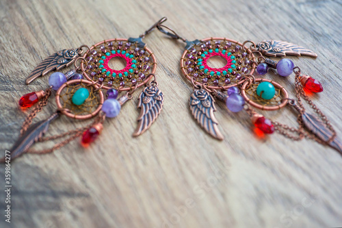 Copper dreamcatcher earrings with amethyst and nephritis stones on the wooden table photo