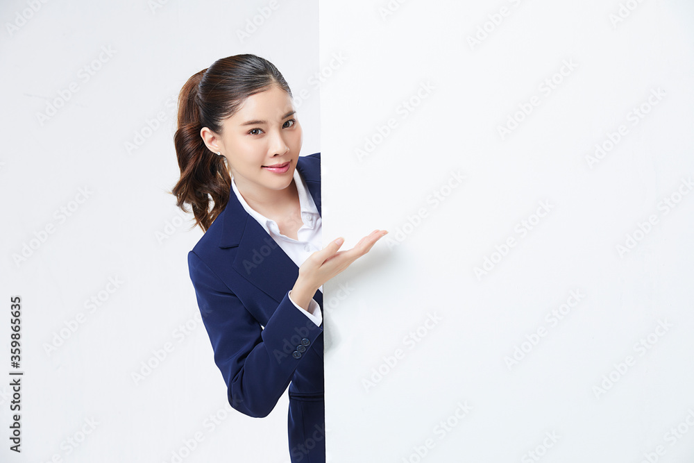 Portrait of young and pretty Asian woman showing something interesting at copy space white wall for your information or advertising content Portrait of young and pretty Asian woman showing something interesting at copy space white wall for your information or advertising content