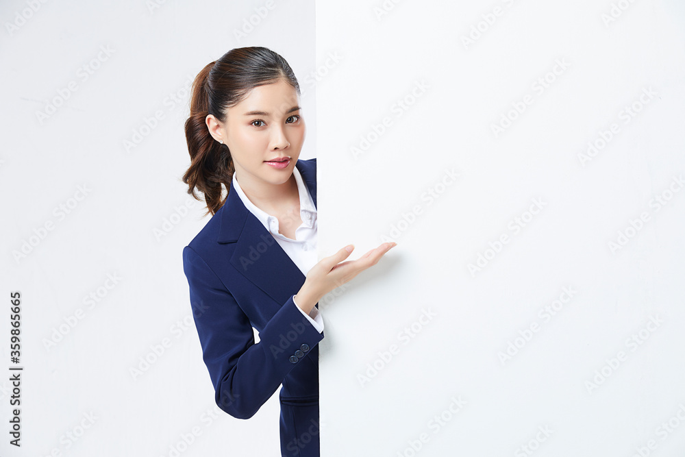 Portrait of young and pretty Asian woman showing something interesting at copy space white wall for your information or advertising content Portrait of young and pretty Asian woman showing something interesting at copy space white wall for your information or advertising content