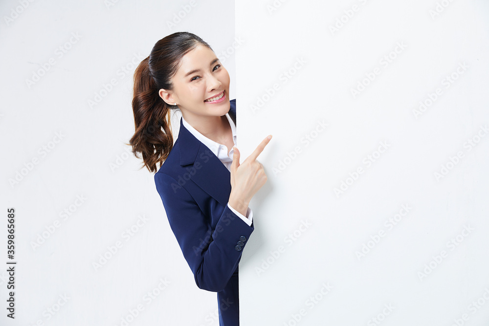Portrait of young and pretty Asian woman showing something interesting at copy space white wall for your information or advertising content Portrait of young and pretty Asian woman showing something interesting at copy space white wall for your information or advertising content