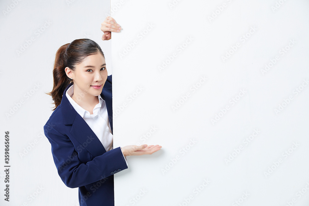 Portrait of young and pretty Asian woman showing something interesting at copy space white wall for your information or advertising content