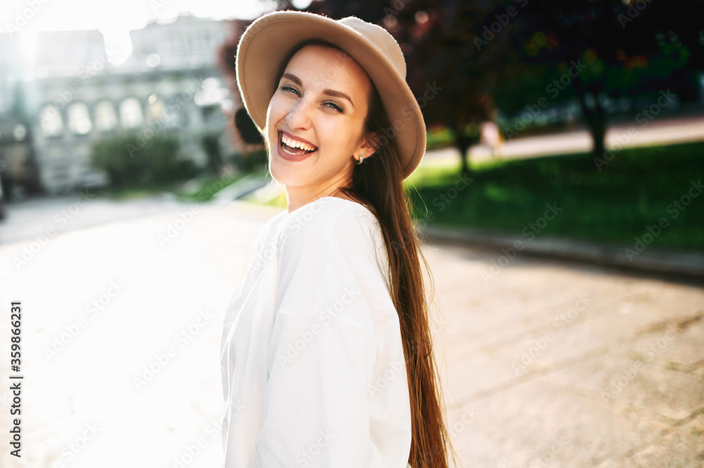 Follow me. Beautiful young woman in hat looks back into camera and smiles