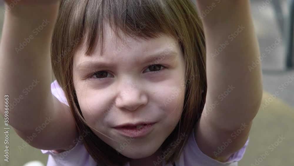 Little funny girl at the training place. The child performs sports exercises with difficulty. Little funny girl at the training place. The child performs sports exercises with difficulty.