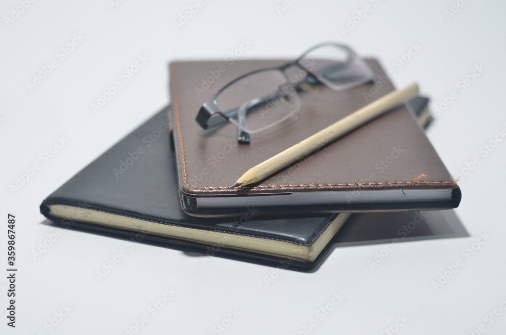 white office desk with notebooks, eyeglass, pencil and glass of water on isolated white background white office desk with notebooks, eyeglass, pencil and glass of water on isolated white background