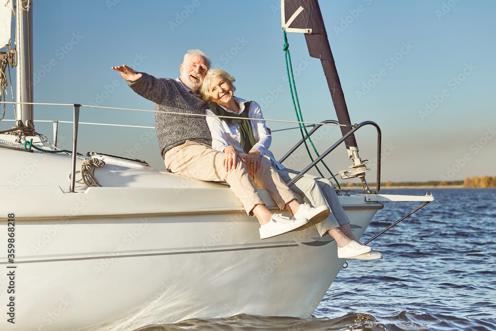 Anchors away. Happy senior couple hugging on sail boat or yacht deck floating in sea. Man hugging his woman while enjoying the view