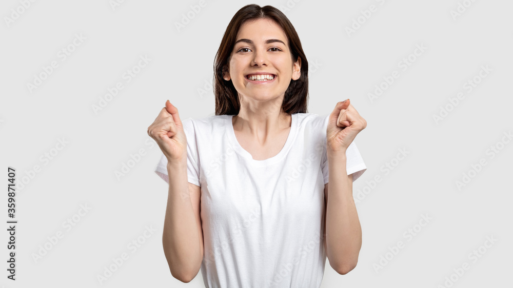 Winning gesture. Victory success. Happy excited woman raising clenched fists isolated on light background. Winning gesture. Victory success. Happy excited woman raising clenched fists isolated on light background.