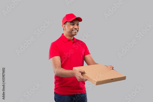 Delivery Man Pizza Box in Hands Watching Side Isolated. Red Tshirt Indian Delivery Boy.